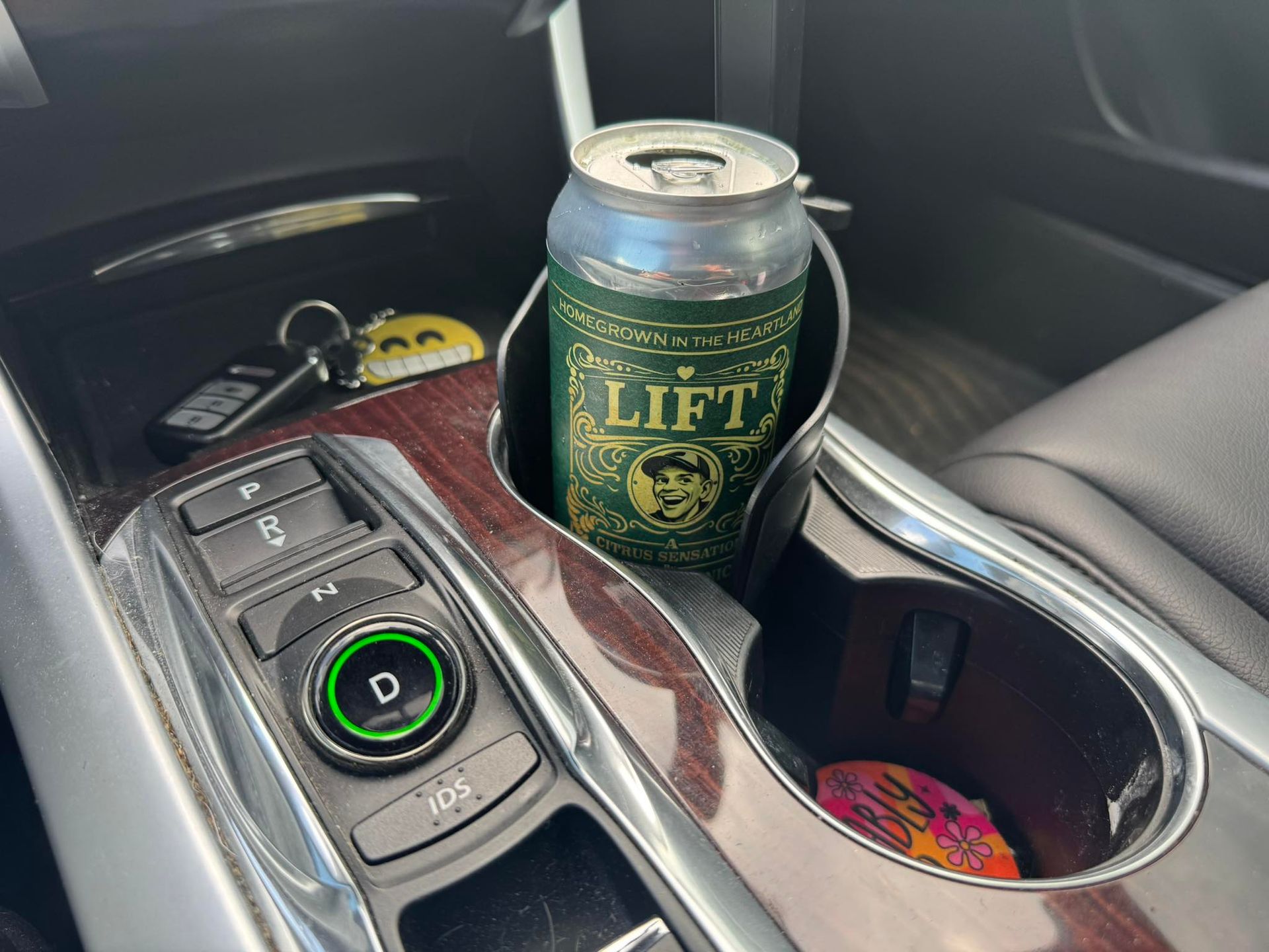Can of Lift on a car center console beside drive controls and a cup holder