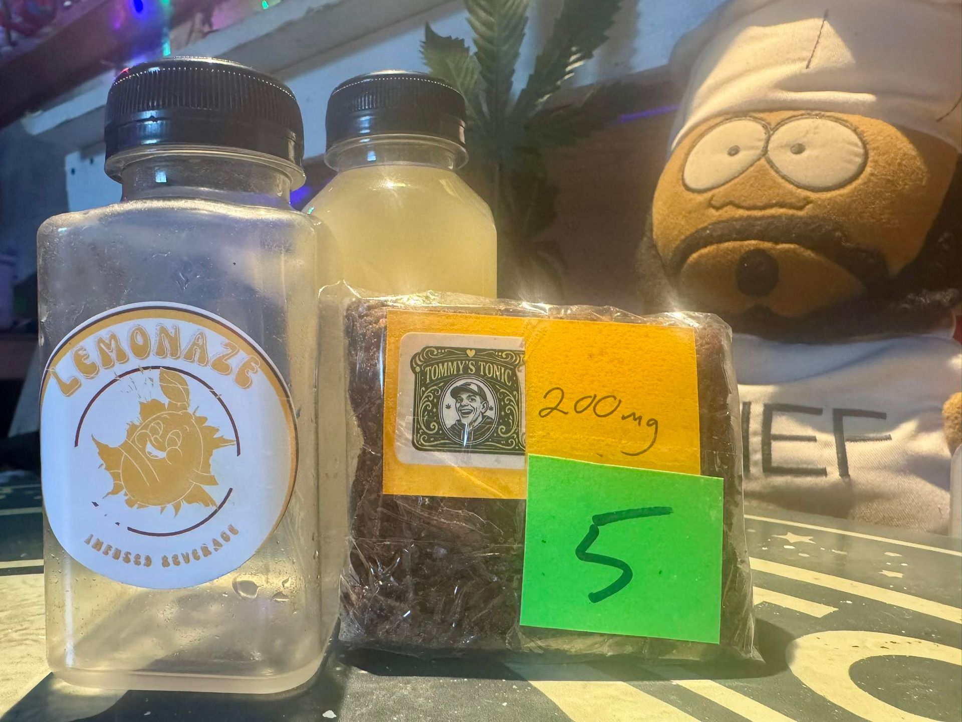 Three bottles on a table, including a clear “Lemonade” bottle and a small bag labeled 200g and 5.