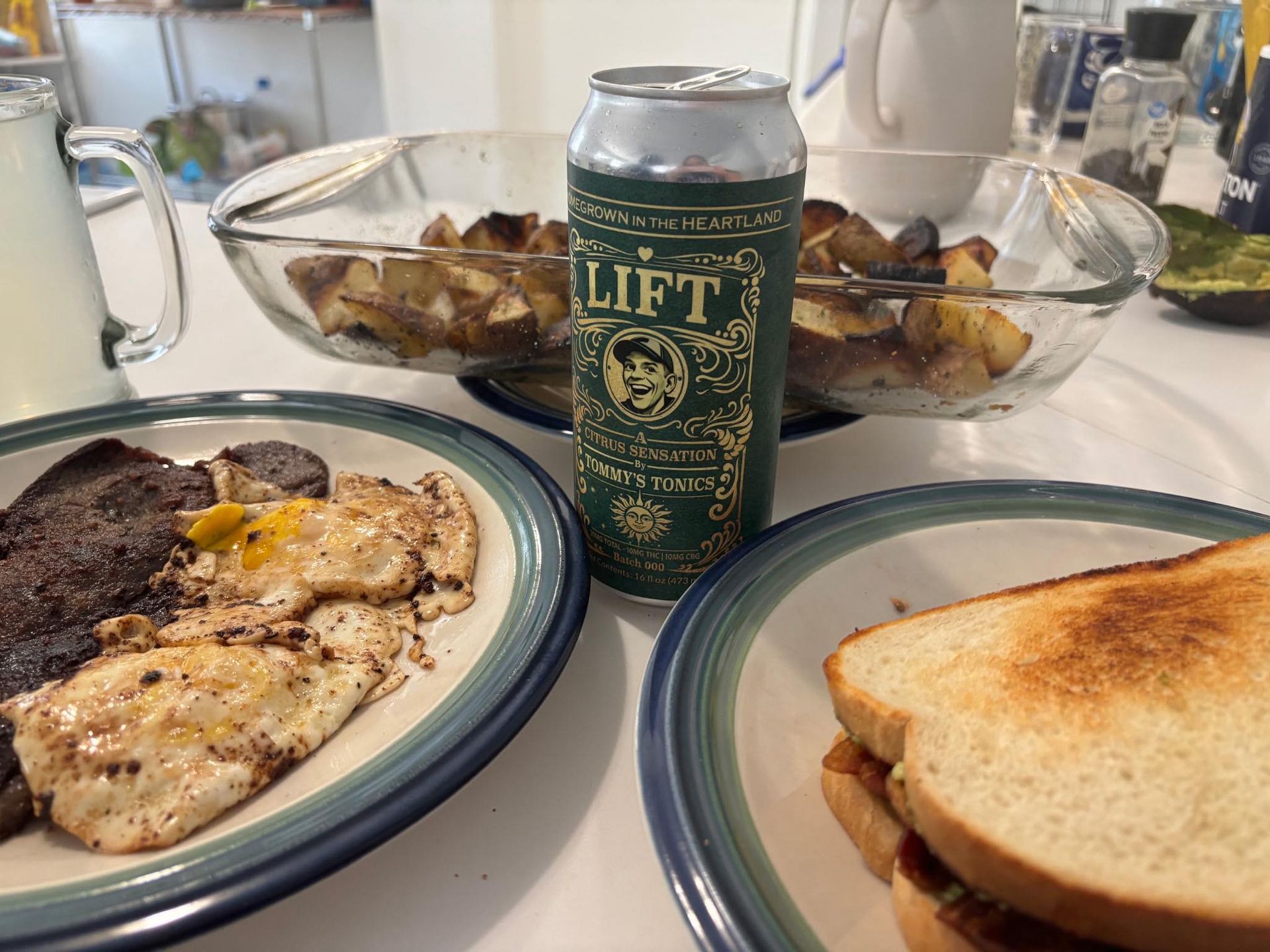 Breakfast table with eggs, toast, and a green Lift can on white plates and glass dishes
