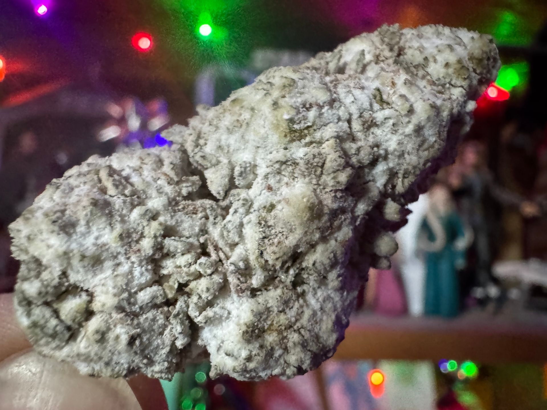 White, lumpy rock centered against a blurred colorful background with red, green, and purple lights