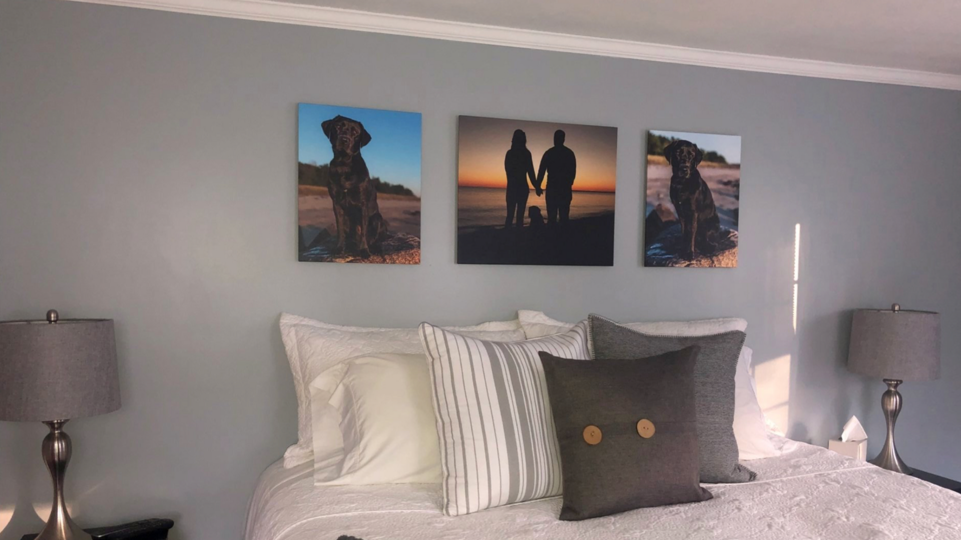Professional pet photography wall art displayed in a bedroom featuring custom portraits of a family dog and owners.