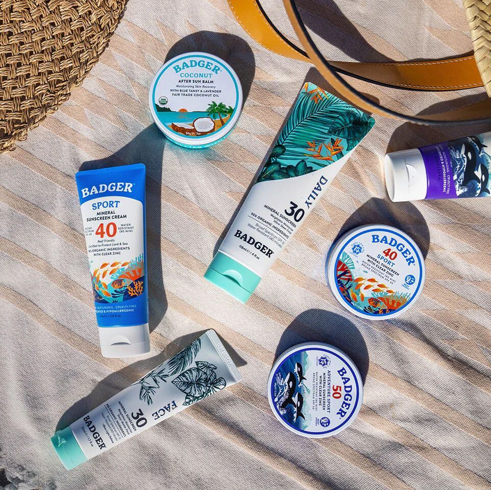 A bunch of badger sunscreens are sitting on a beach towel.