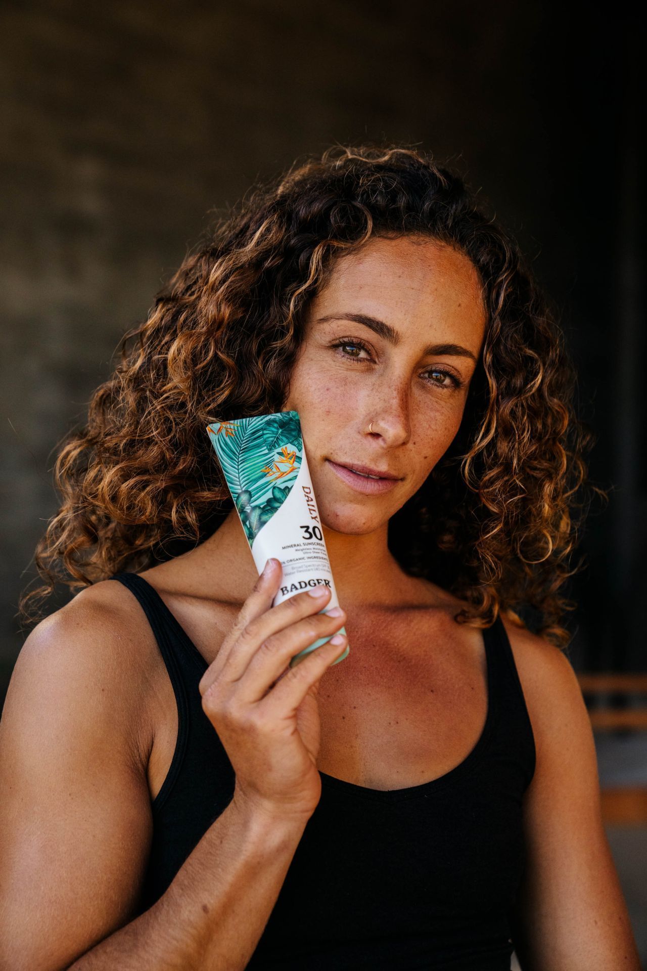 A woman with curly hair is holding a chocolate bar in her hand.