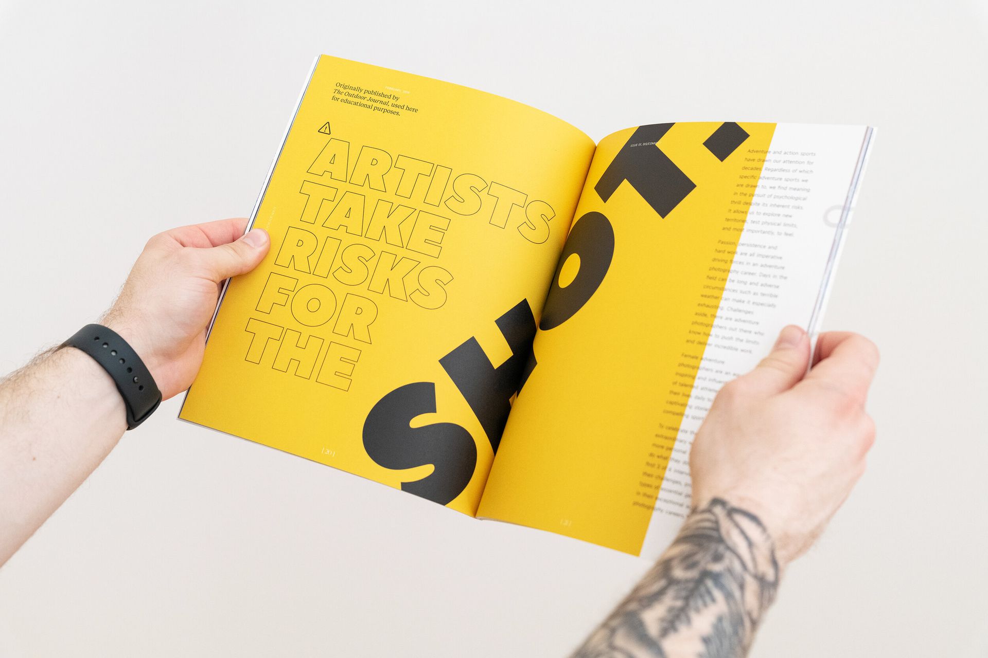 A person with a tattoo on their arm is reading a yellow book.