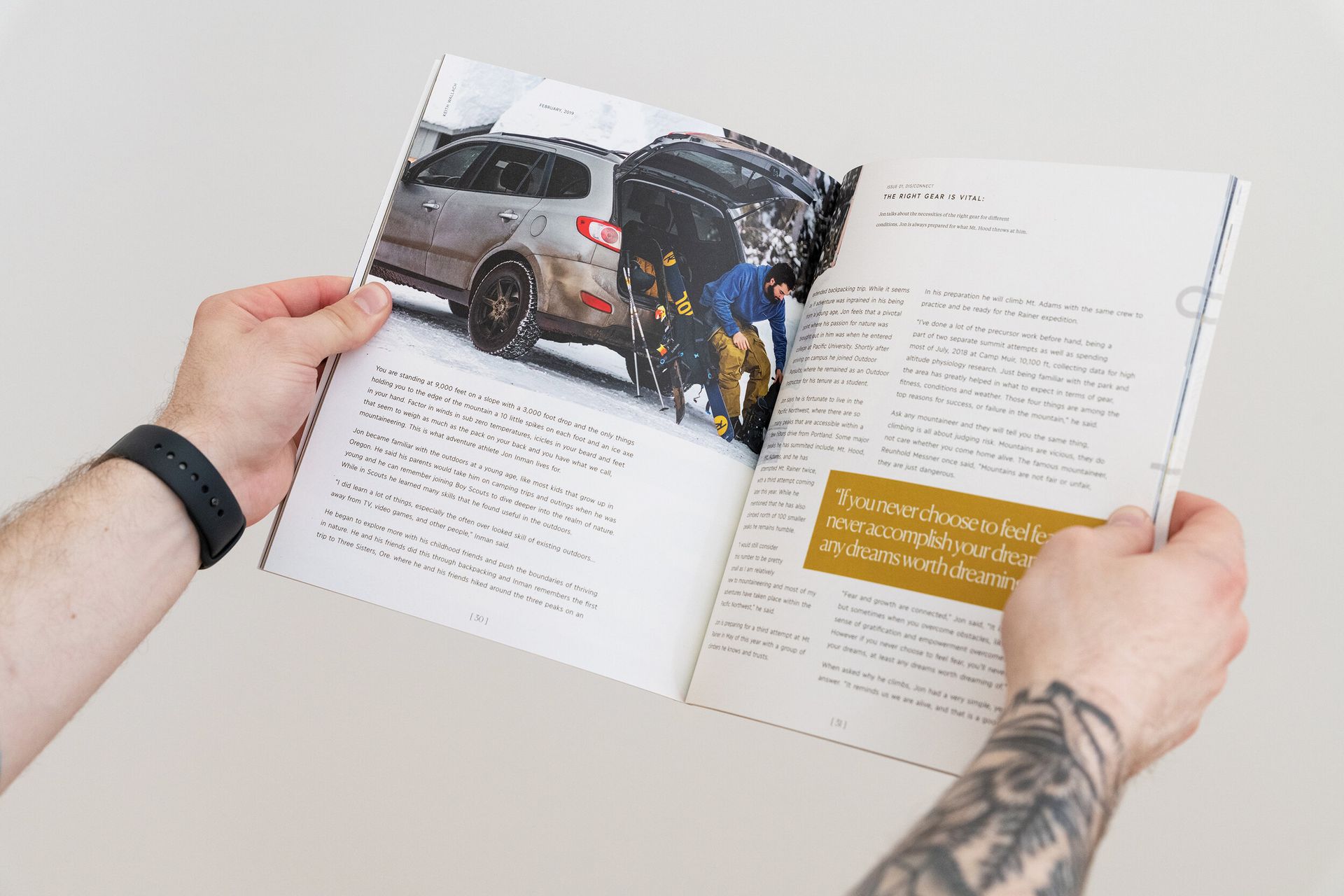 A person is holding a magazine with a picture of a car on the cover.