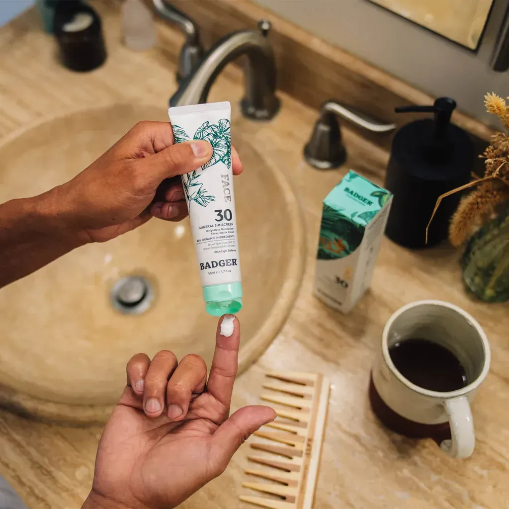 A person is applying lotion to their finger in a bathroom