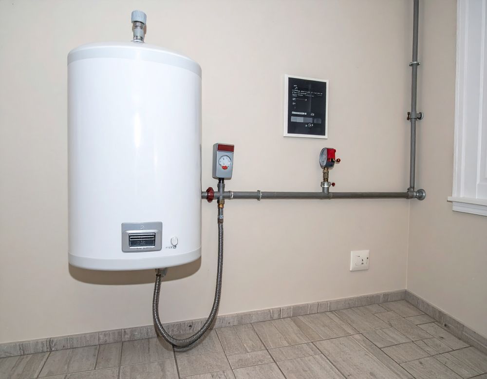 White water heater mounted on a wall with exposed plumbing in a tiled utility room.