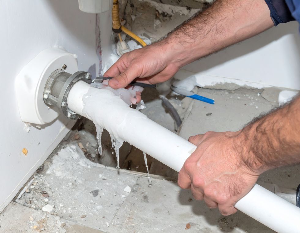 A person applies adhesive tape to a leaking white pipe connection attached to a white water heater.