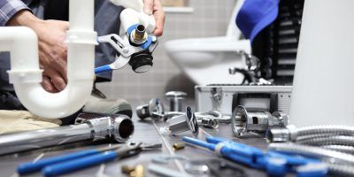 Plumber repairing sink pipes with tools on a countertop in a kitchen-like workspace