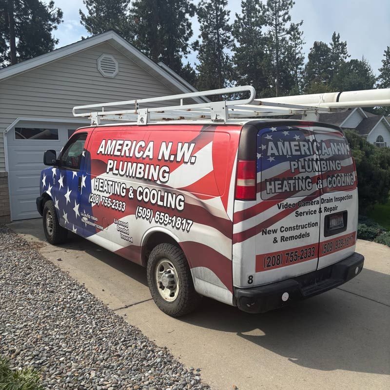 American N.W. Plumbing & Heating van with U.S. flag wrap parked in a driveway by a garage