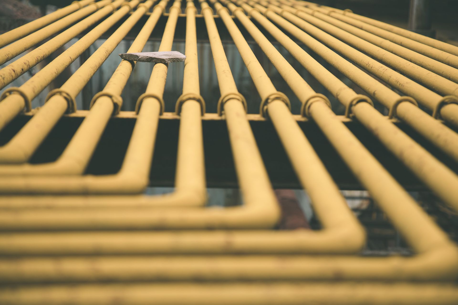 Rows of yellow pipes running diagonally across the frame in a repeating industrial pattern
