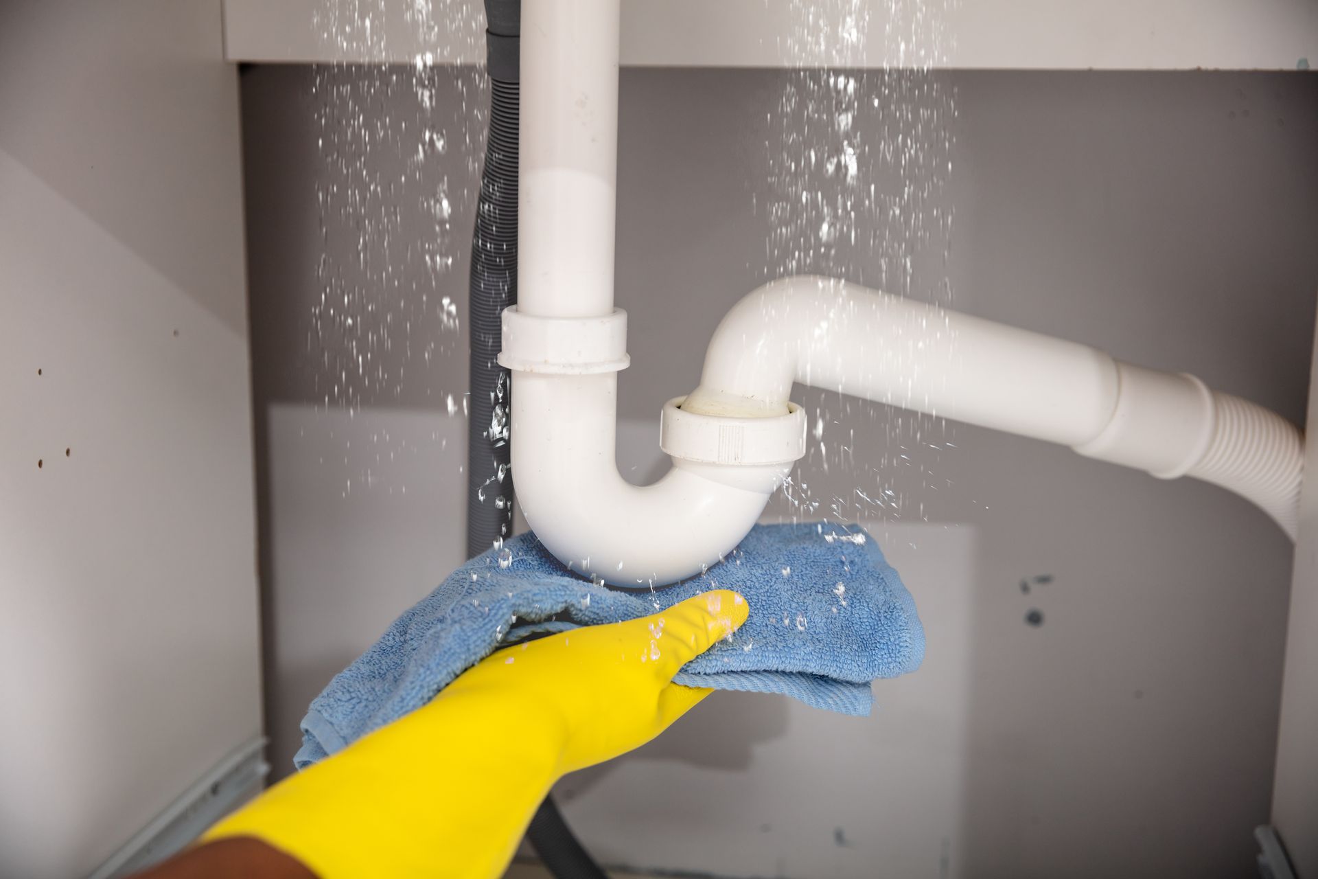 White PVC plumbing pipes connected in an S-shape trap configuration against a dark wooden background.