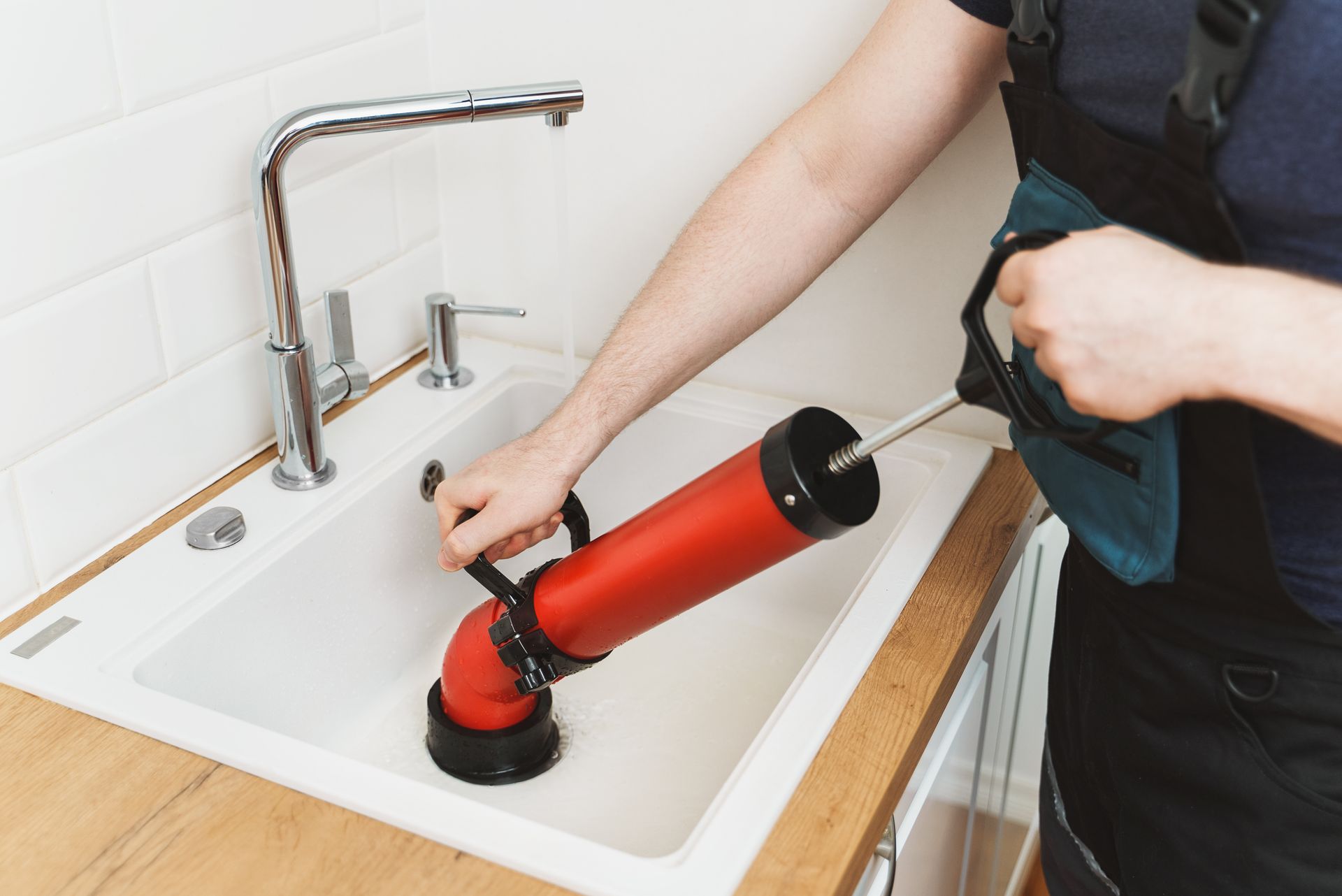 A technician wearing work clothes inspects a wall-mounted water heater and makes notes on a clipboard.