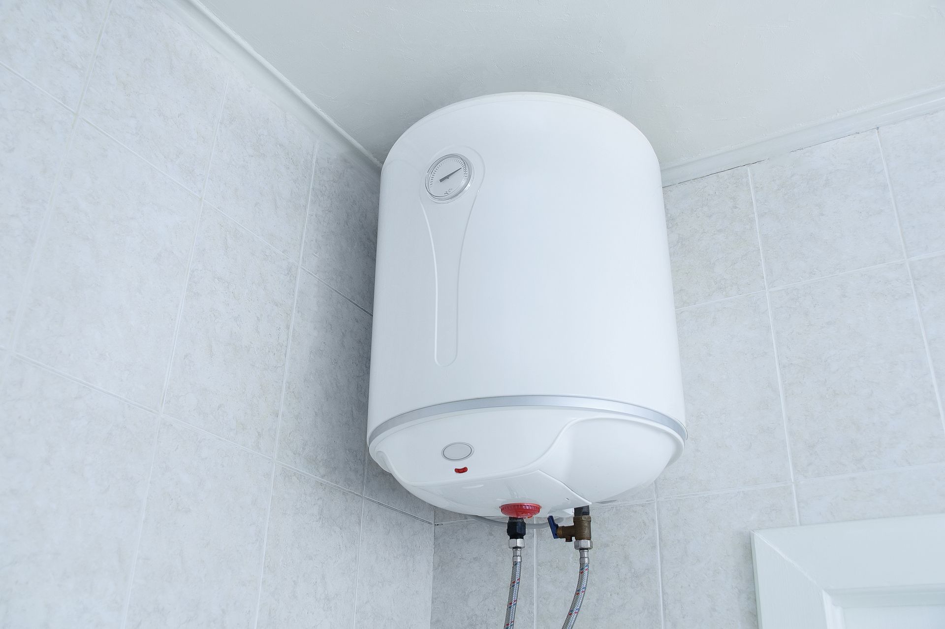 White electric water heater mounted on a tiled wall.
