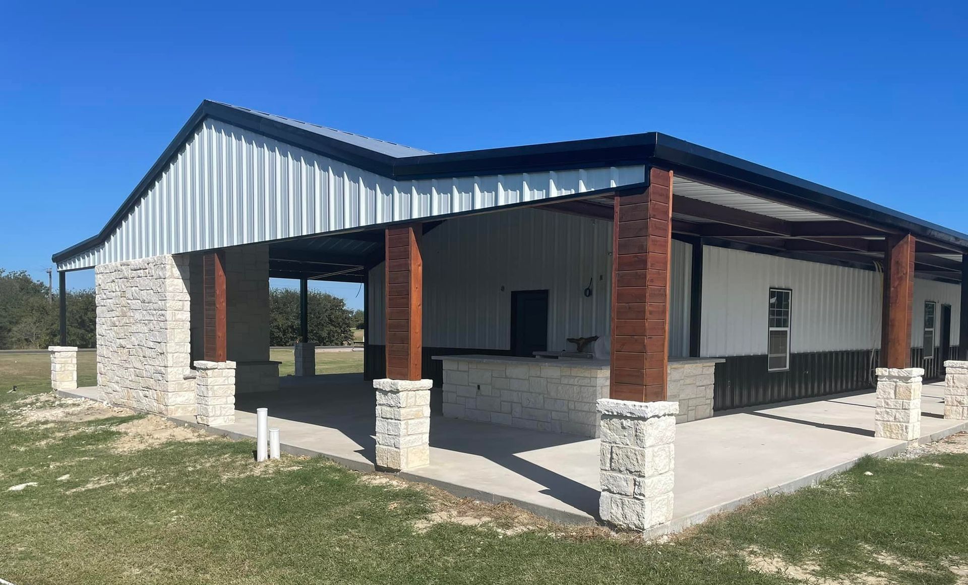 Single-story brick and metal building with a covered porch and white columns on a grassy lot