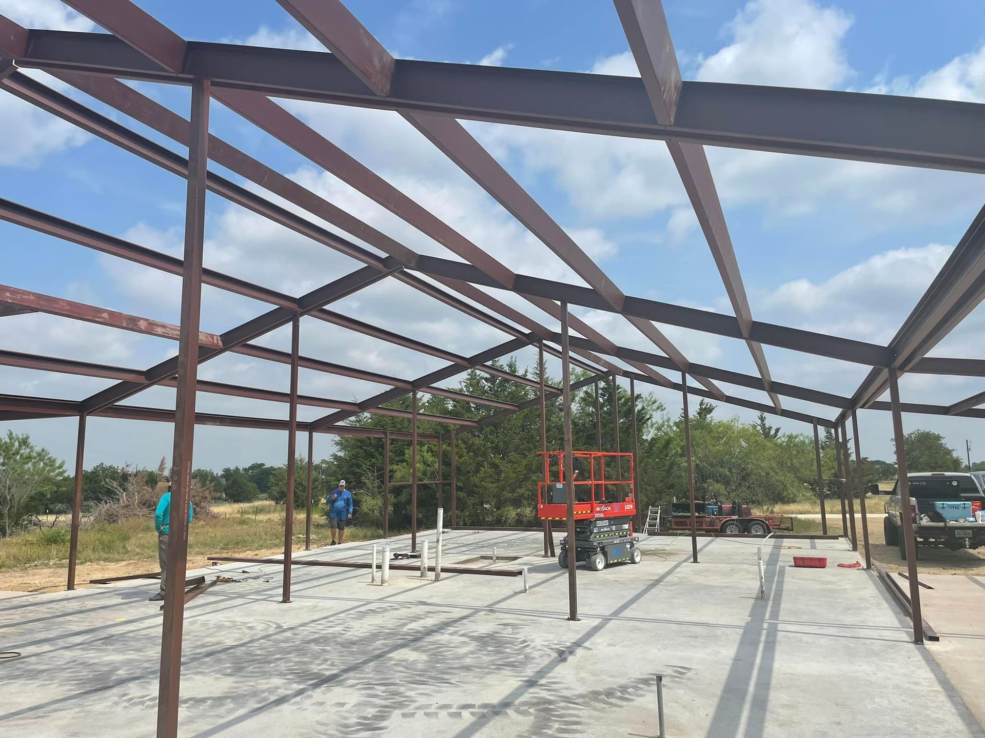 Steel frame building under construction with concrete floor and blue sky overhead