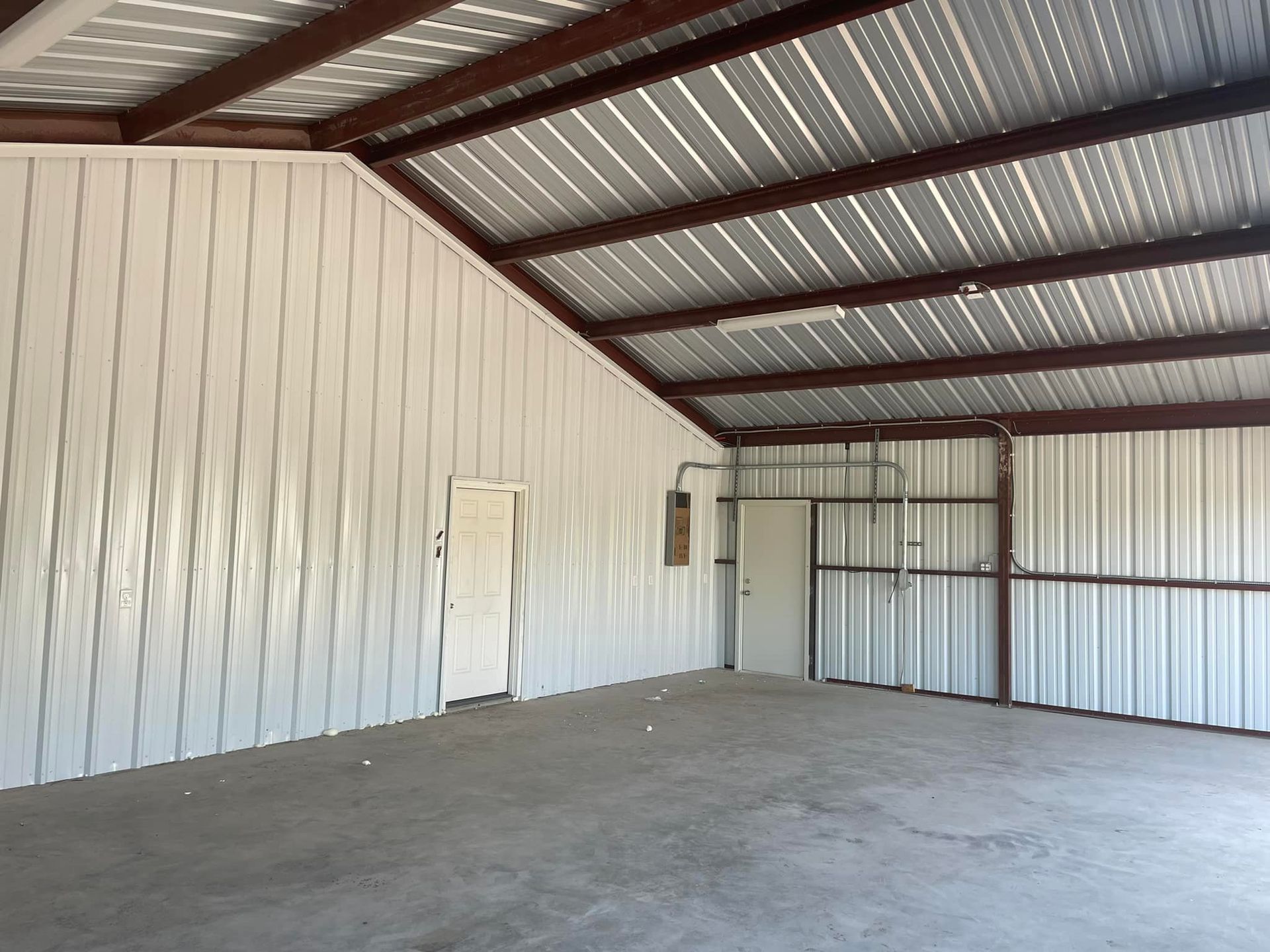 Empty metal-walled warehouse interior with concrete floor and corrugated roof beams