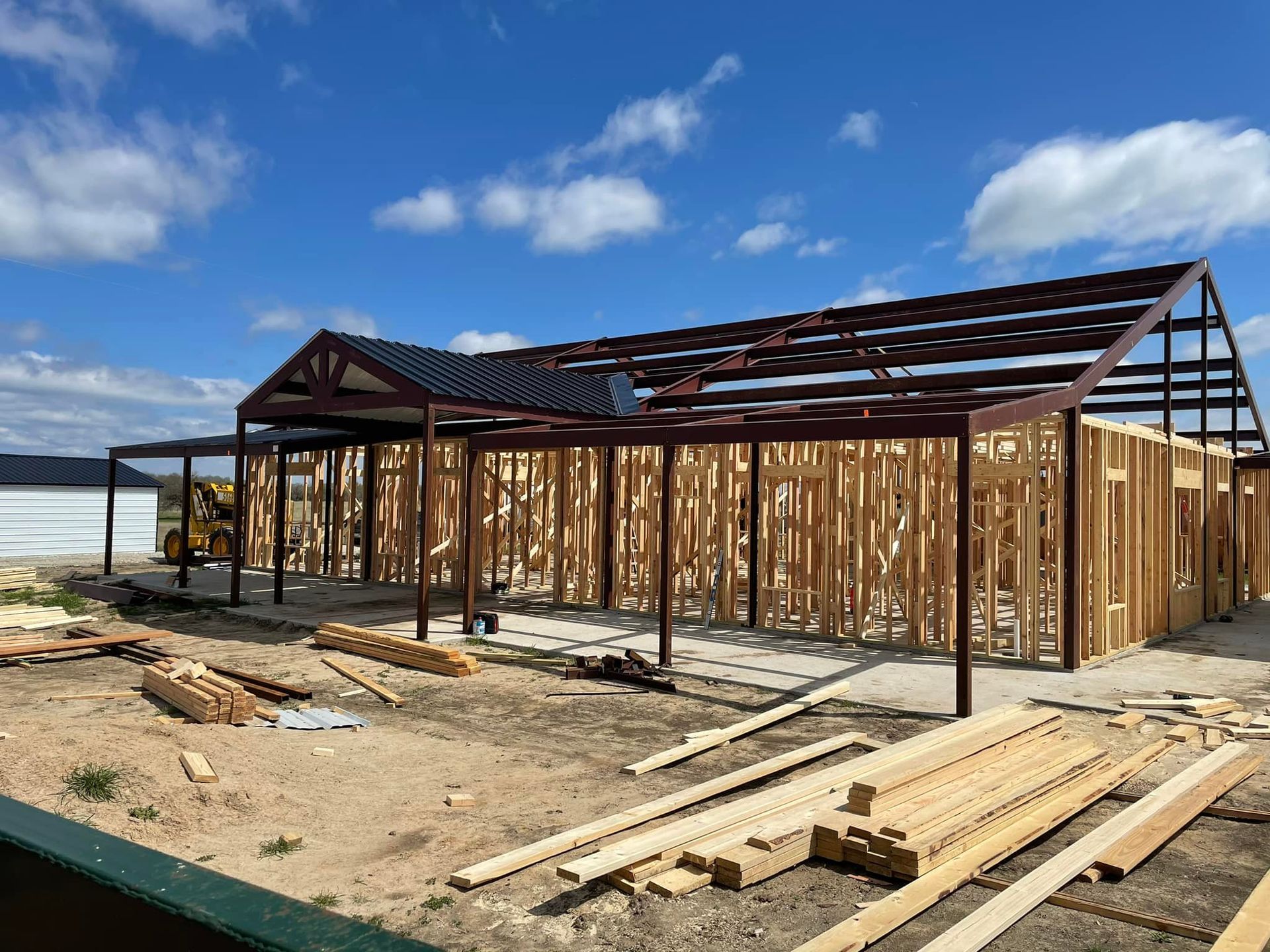 Partially built wooden house frame on a sandy beach under a blue sky