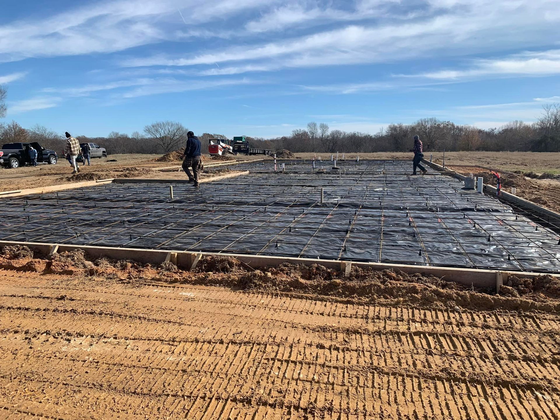 Construction site with workers laying a large concrete slab under a blue sky