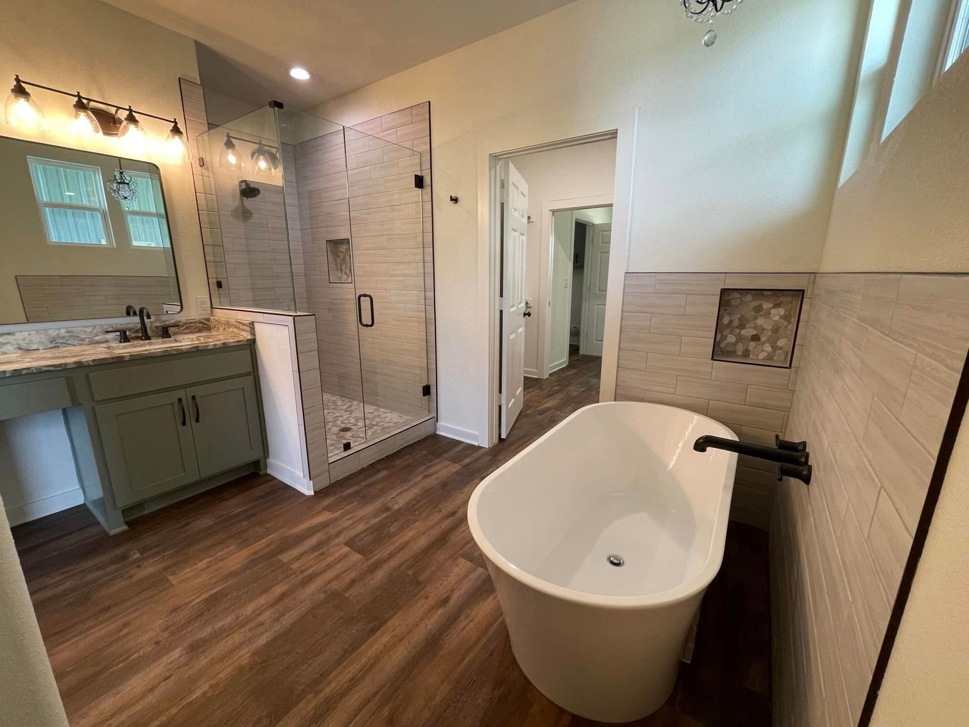 Modern bathroom with a freestanding tub, walk-in shower, vanity, and wood-look floor.