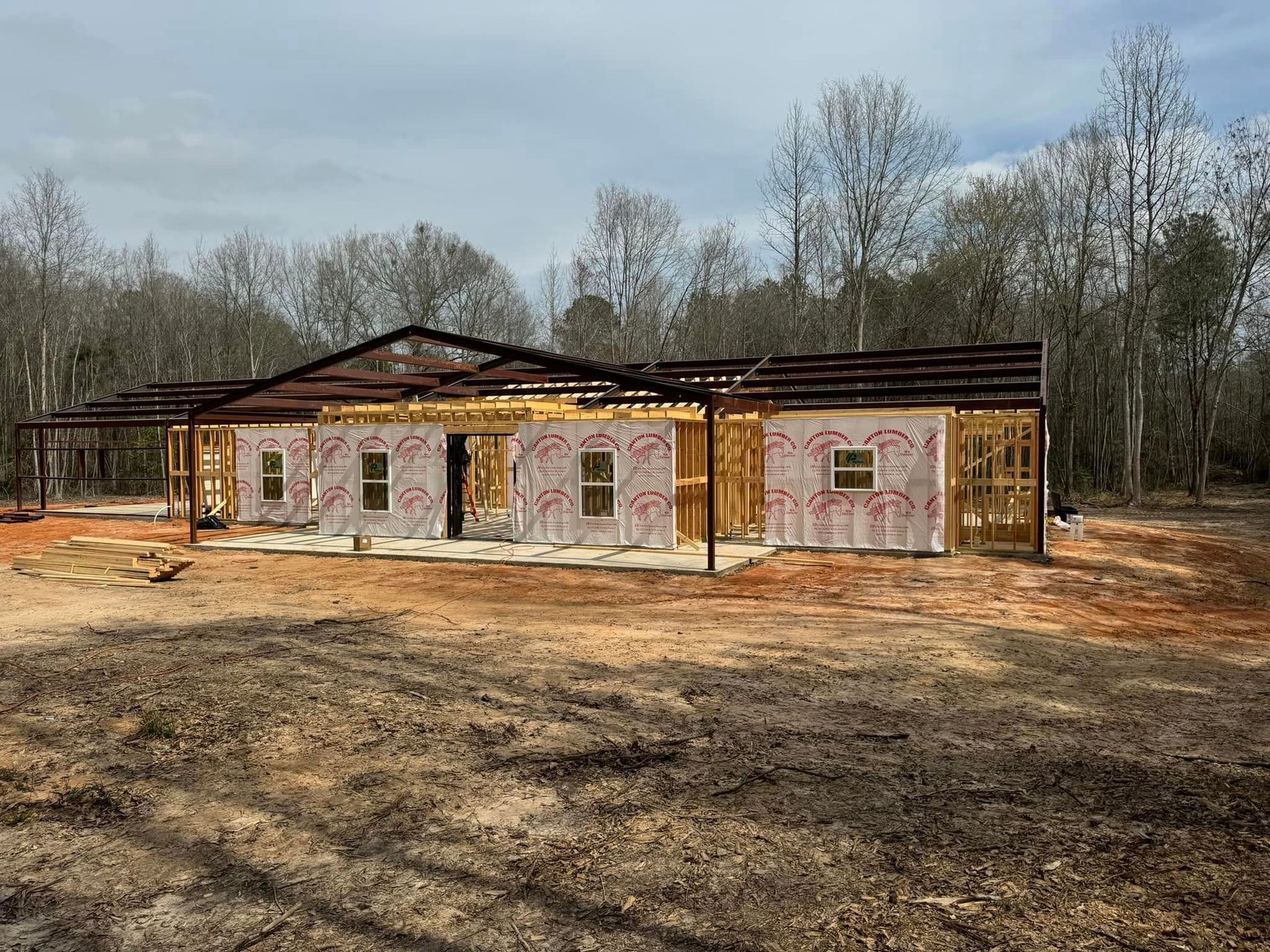 Partially built house in a wooded clearing, with exposed framing and unfinished exterior walls