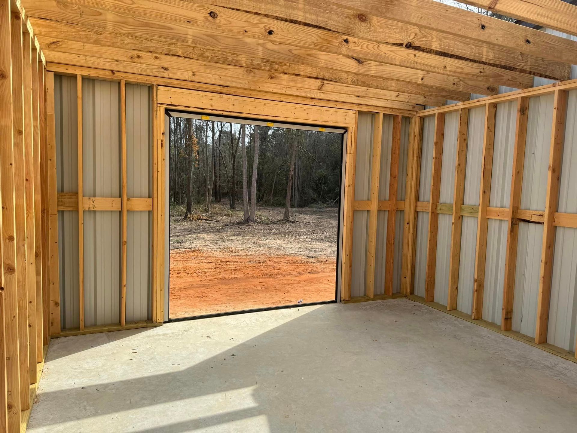 Empty wooden-framed room with a concrete floor and open doorway to the outdoors