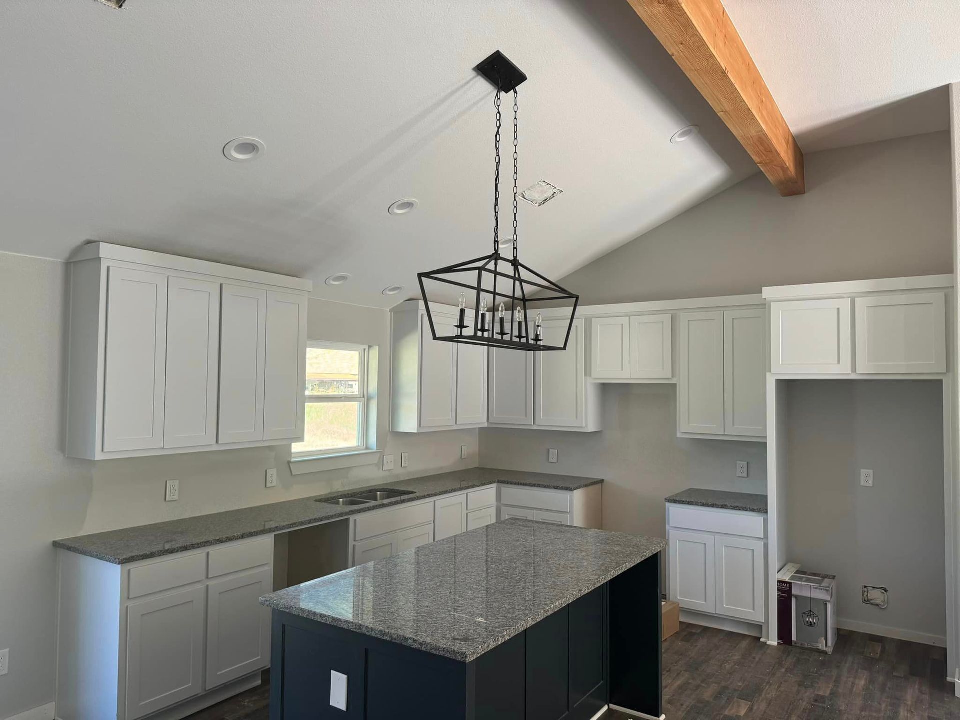 Modern kitchen with white cabinets, gray countertops, island, and pendant light under a vaulted ceiling