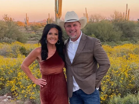 Couple posing in a desert field at sunset, with yellow wildflowers and cactus in the background.