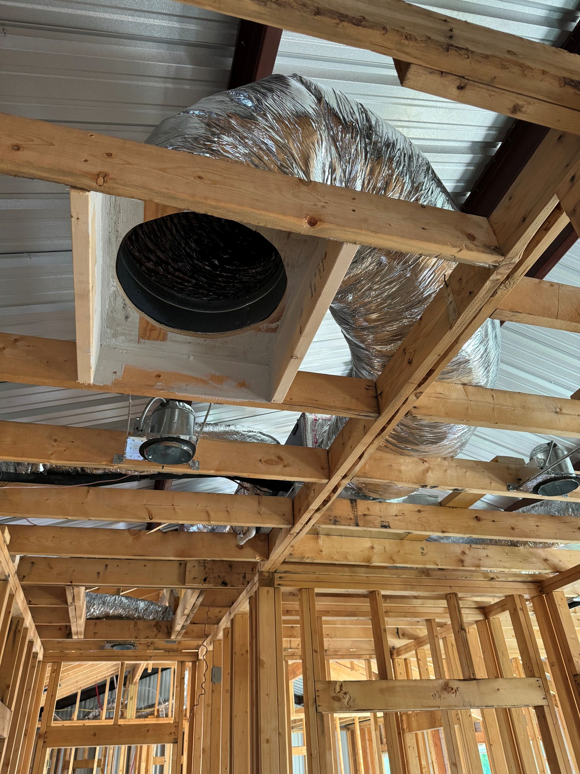 Exposed ceiling framing with HVAC ducts and vents in an unfinished building under construction