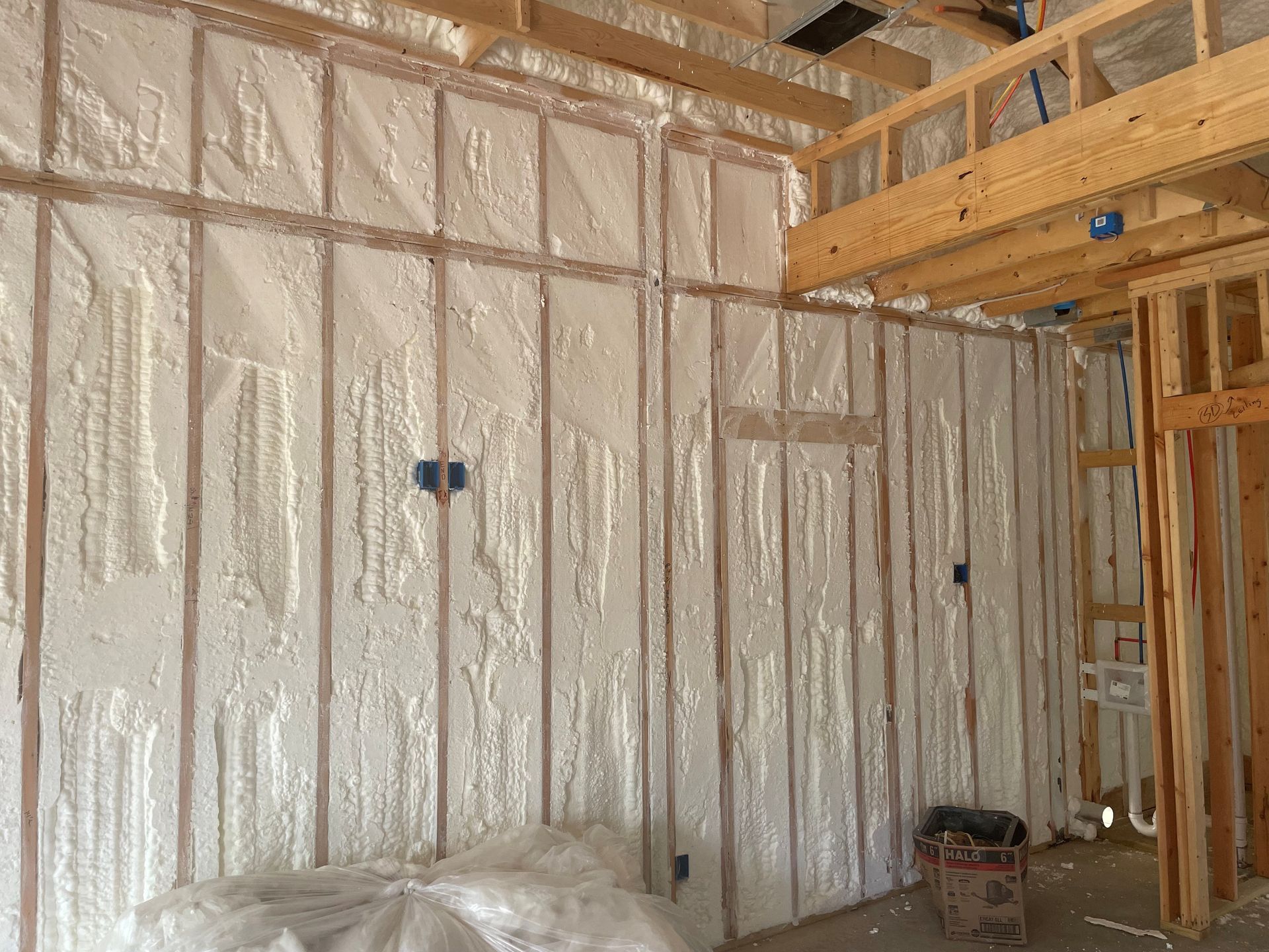 Partially finished room with insulated walls, exposed wood framing, and construction materials on the floor