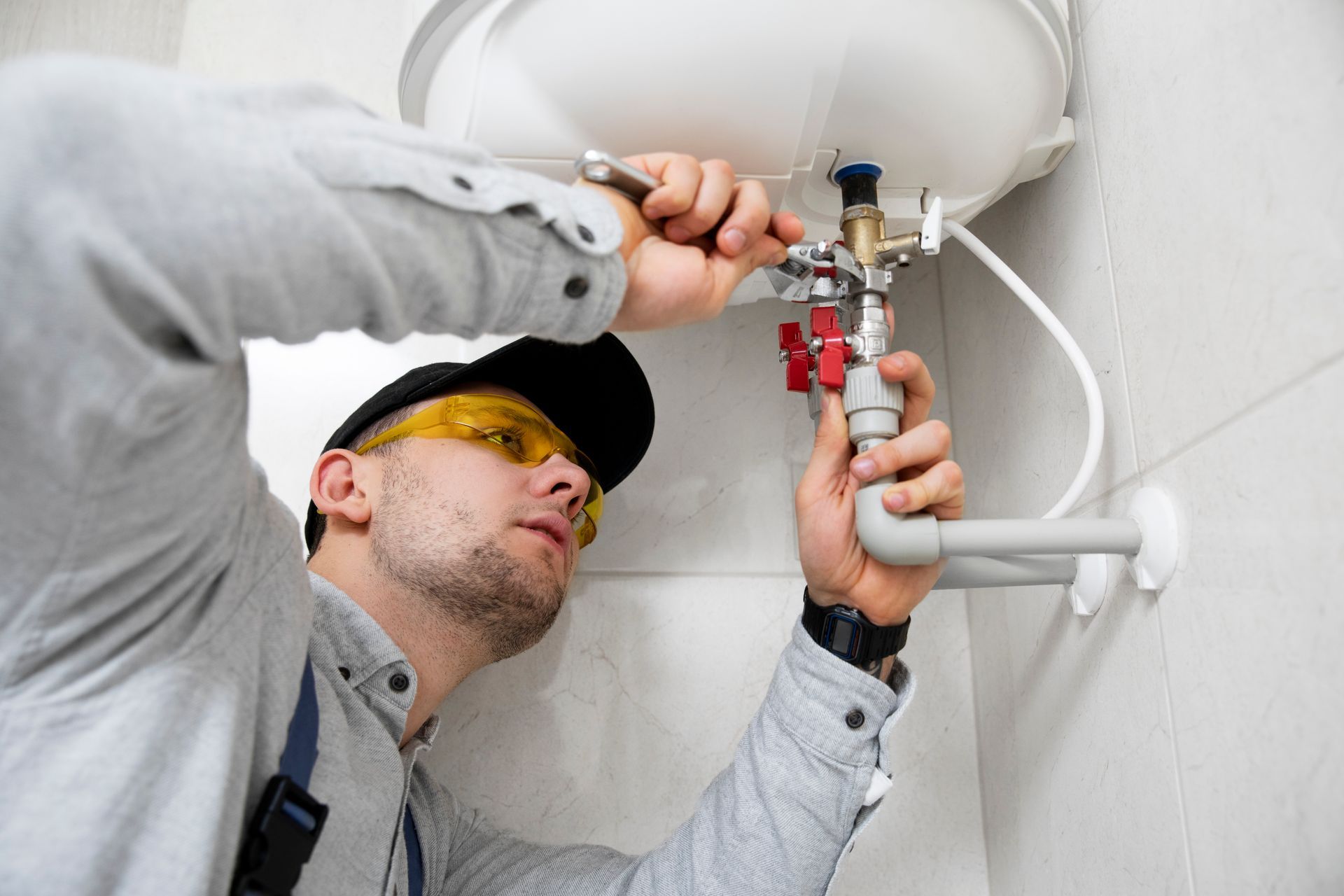 Person adjusting a knob on a white water heater, close-up view.