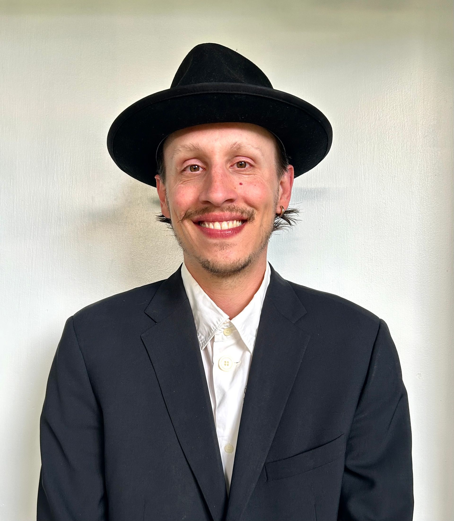A man in a suit and hat is smiling for the camera.