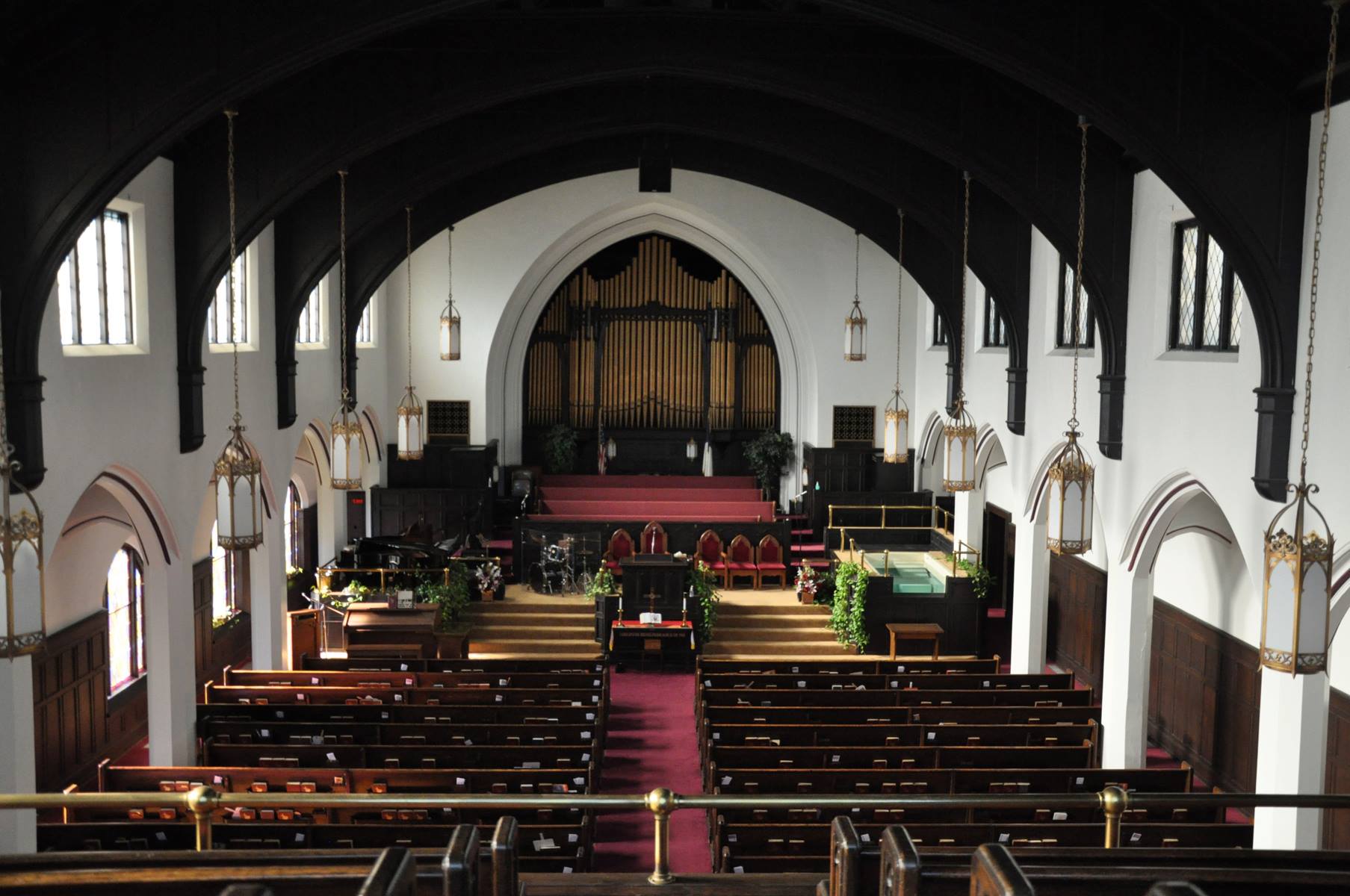 The inside of a church with rows of pews and a red carpet