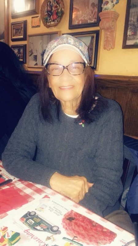 A woman wearing glasses and a hat is sitting at a table in a restaurant.