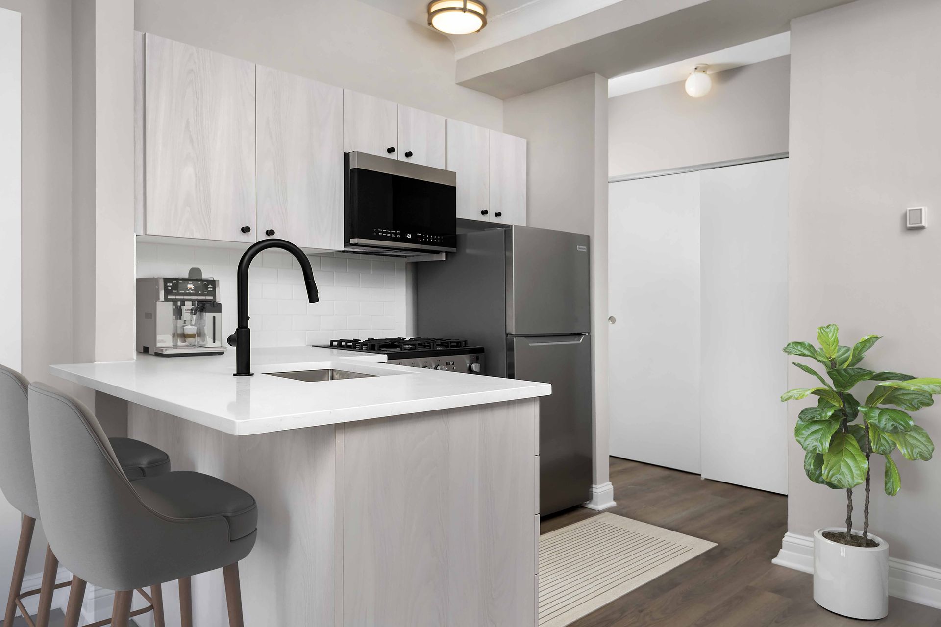 A modern kitchen with a white countertop and grey chairs.