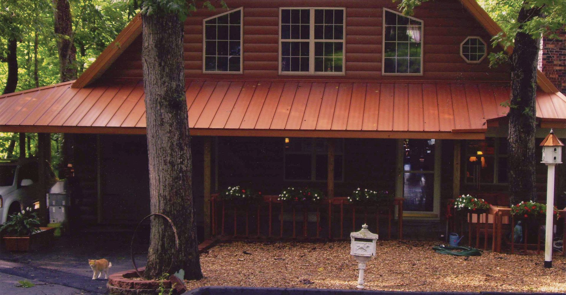 A log cabin with a red roof and a mailbox in front of it