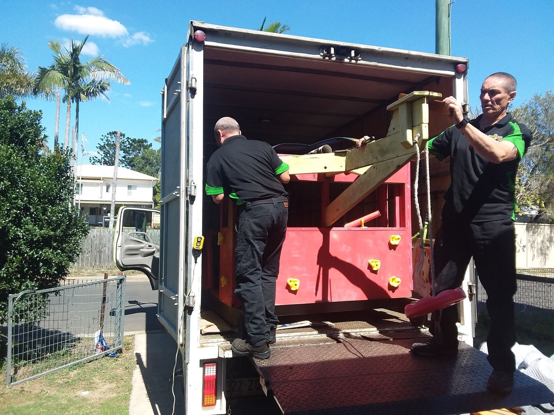 Two Workers Load a Large Red Machine Into a Truck — Little Green Truck Bundaberg In Woodgate, QLD