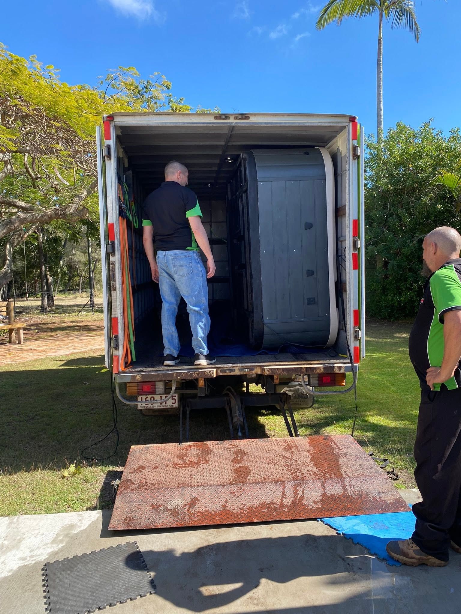 Two Workers Load Furniture Into a Box Truck on A Sunny Day, with A Ramp at The Rear — Little Green Truck Bundaberg in Toogoom, QLD