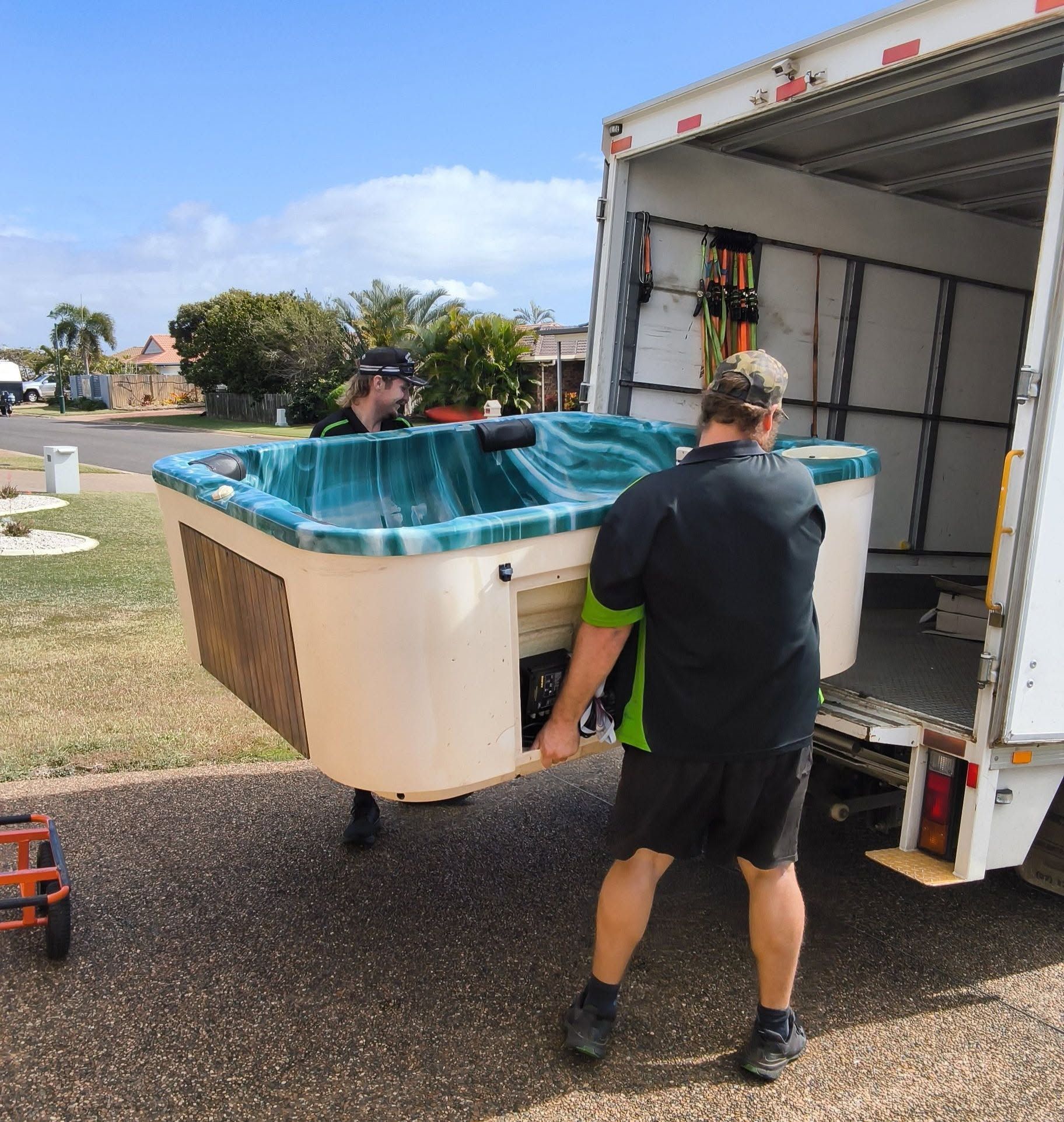 Two Workers Unloading a Blue Hot Tub from A Moving Truck Outdoors — Little Green Truck Bundaberg in Woodgate, QLD