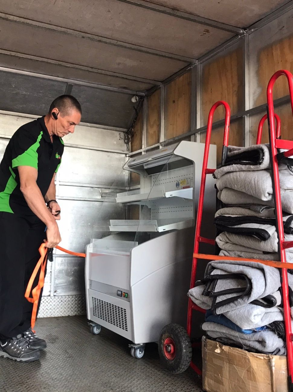 Man Loading a Truck With a Red Dolly, Stacked Boxes, and a White Appliance  — Little Green Truck Bundaberg In Moore Park, NSW