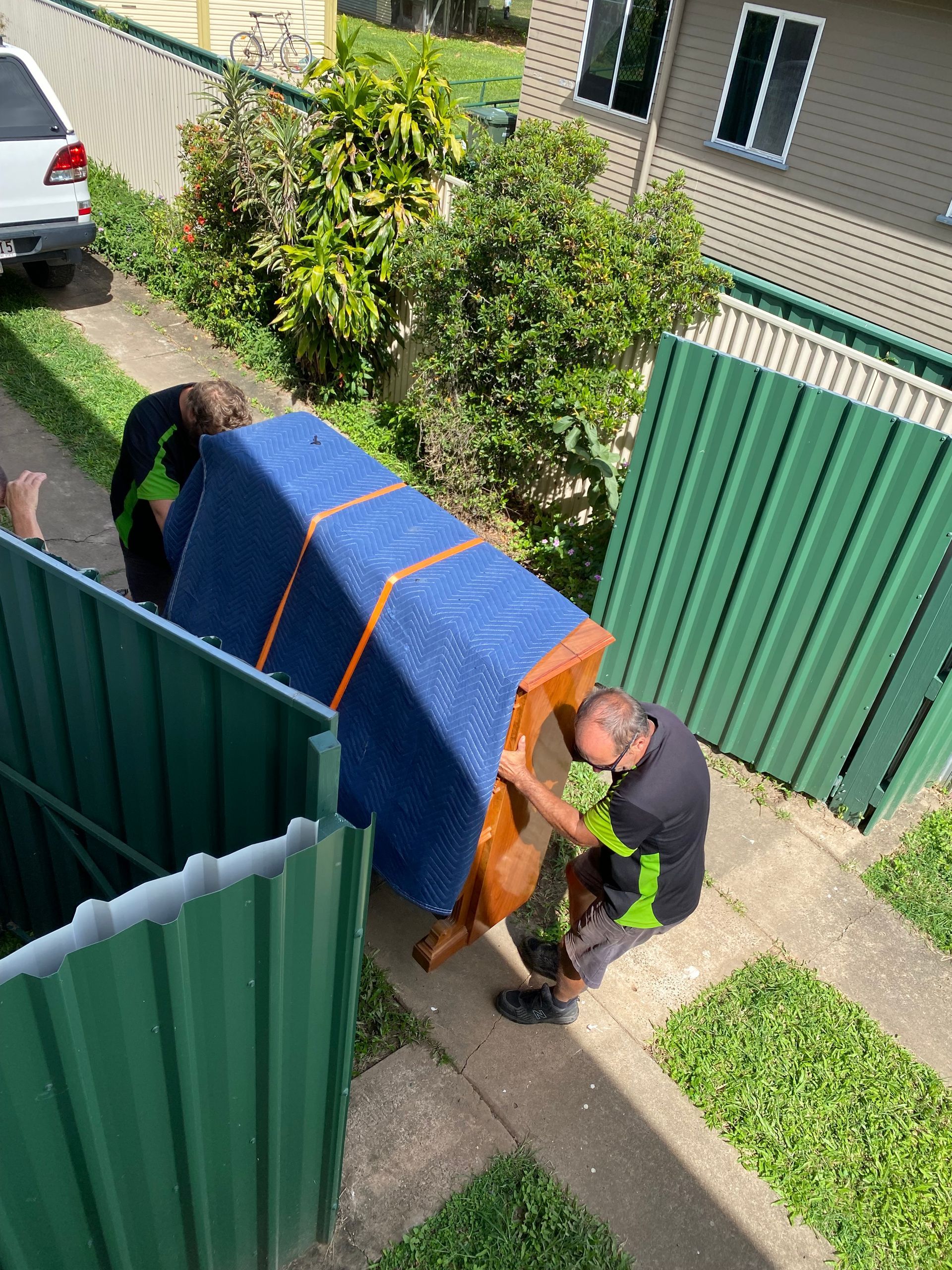 Worker Pushing a Hand Truck Loaded with Boxes Beside a Green Moving Truck on A Street — Little Green Truck Bundaberg in Burrum Heads, QLD