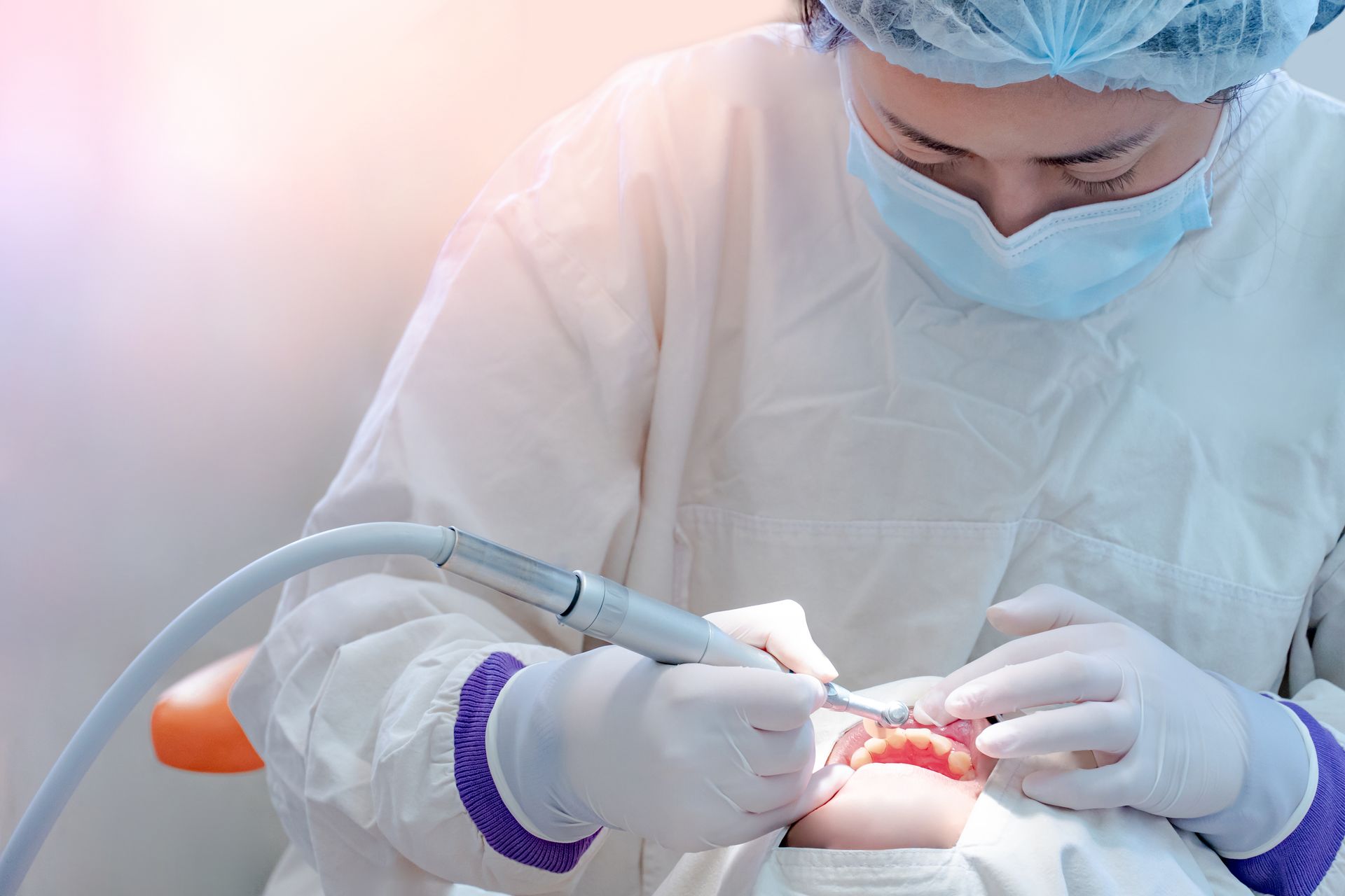 A dental professional performing teeth cleaning with an ultrasonic tool on a patient in a clinic A dental professional performing teeth cleaning with an ultrasonic tool on a patient in a clinic