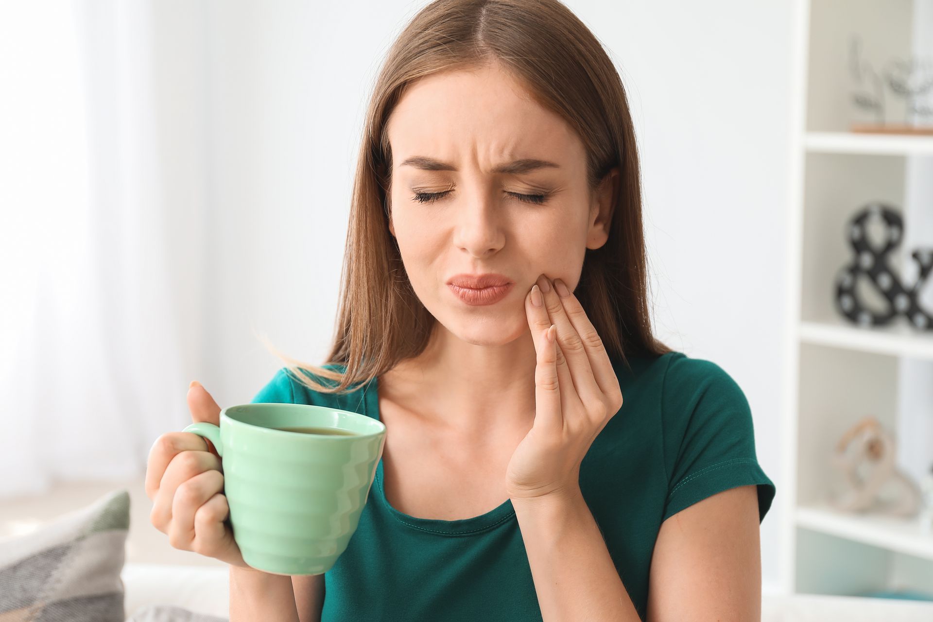 Young woman with sensitive teeth and cup of hot coffee at home. Young woman with sensitive teeth and cup of hot coffee at home.