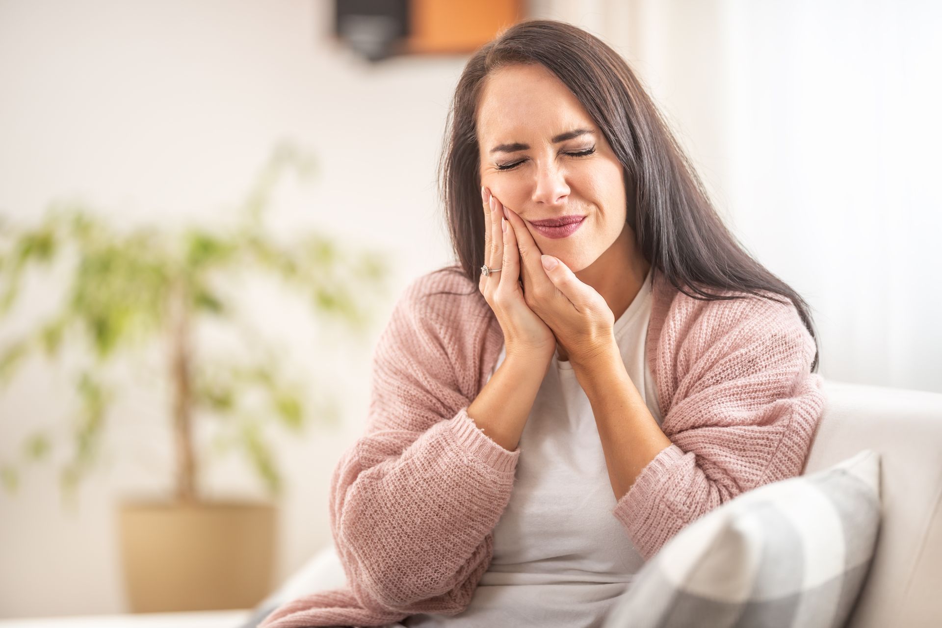 Brunette sits at home with a toothache holding her right cheek with hands. Brunette sits at home with a toothache holding her right cheek with hands.