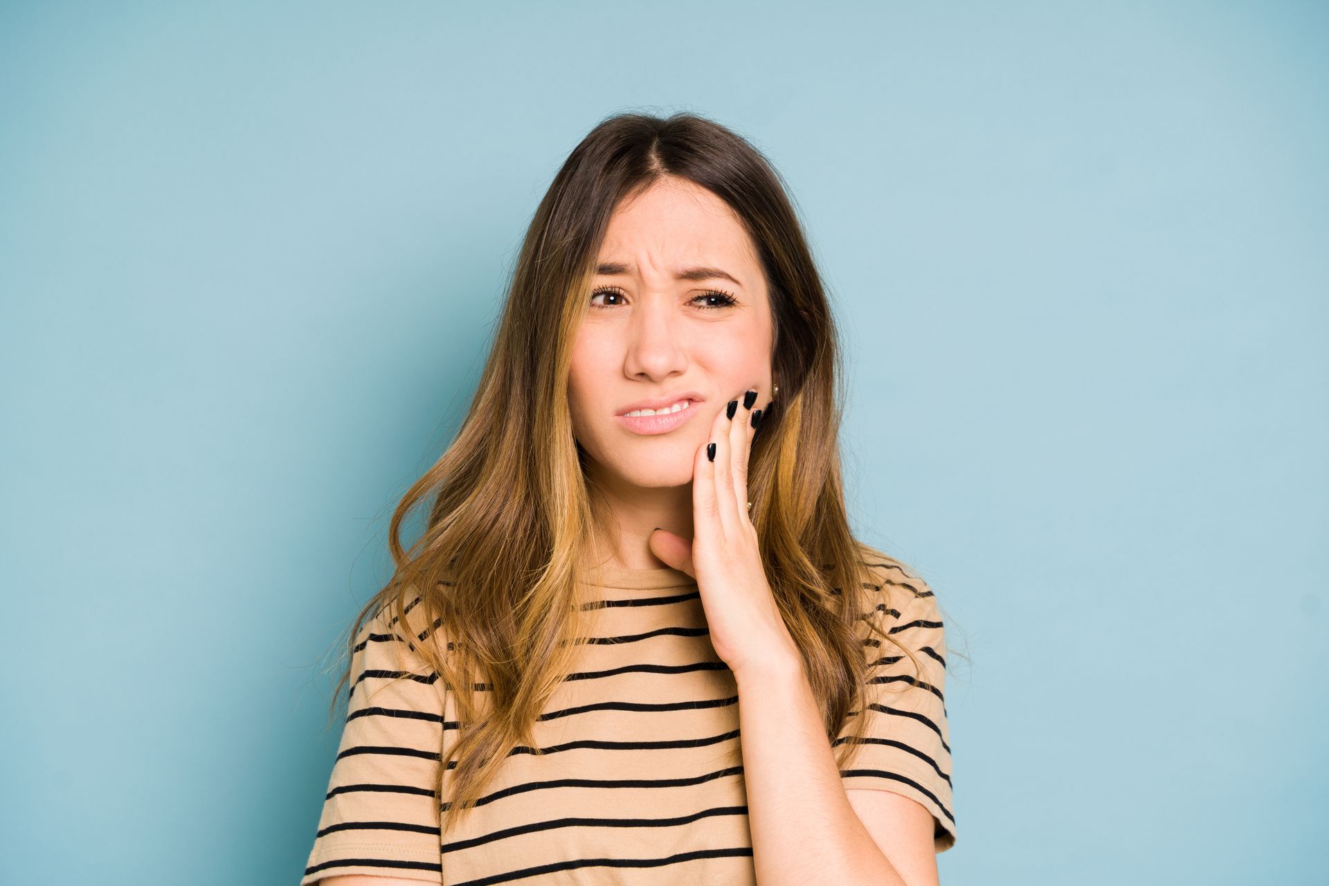 Woman holding her jaw due to toothache or dental pain