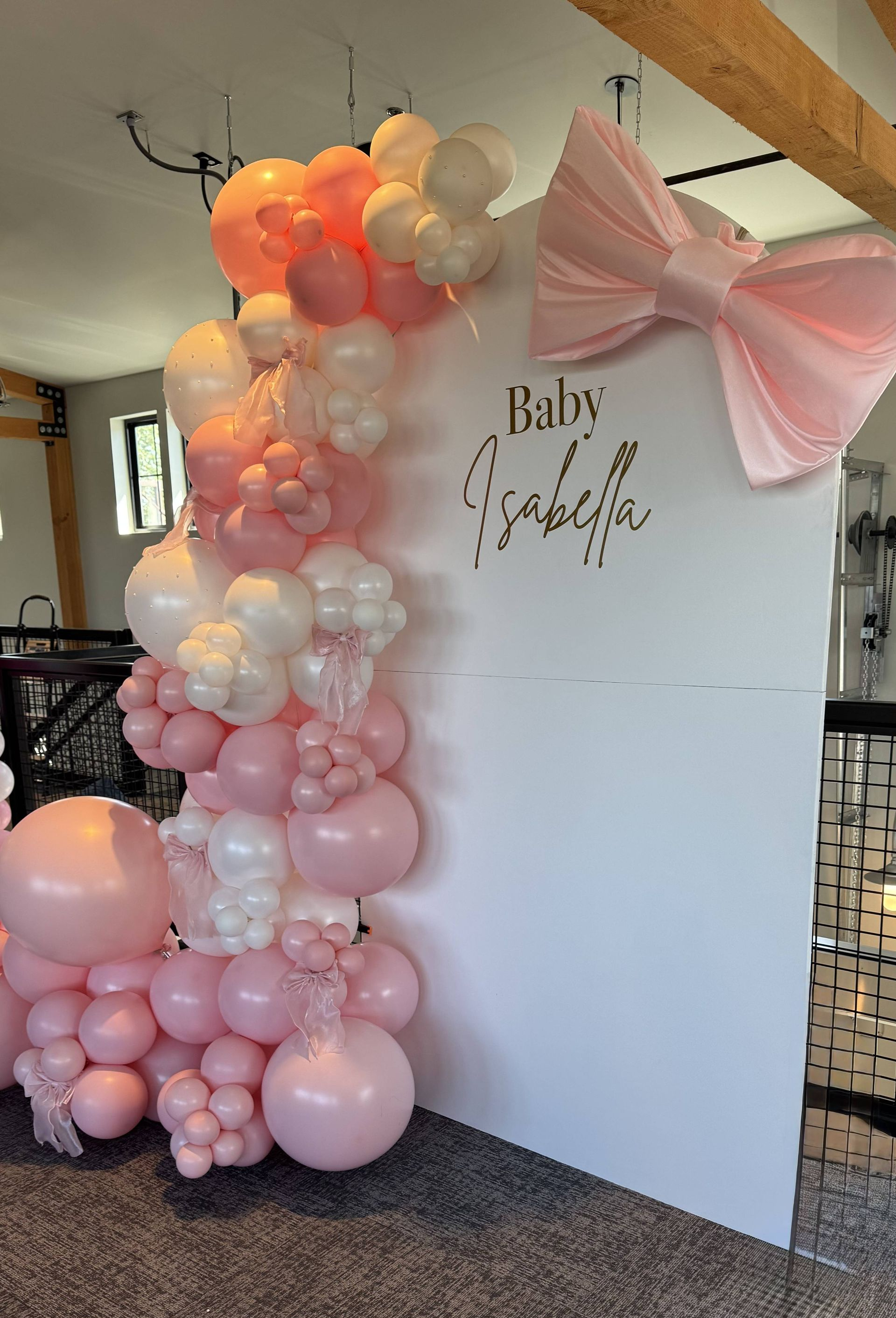 Baby shower celebration with white and pink balloon arch