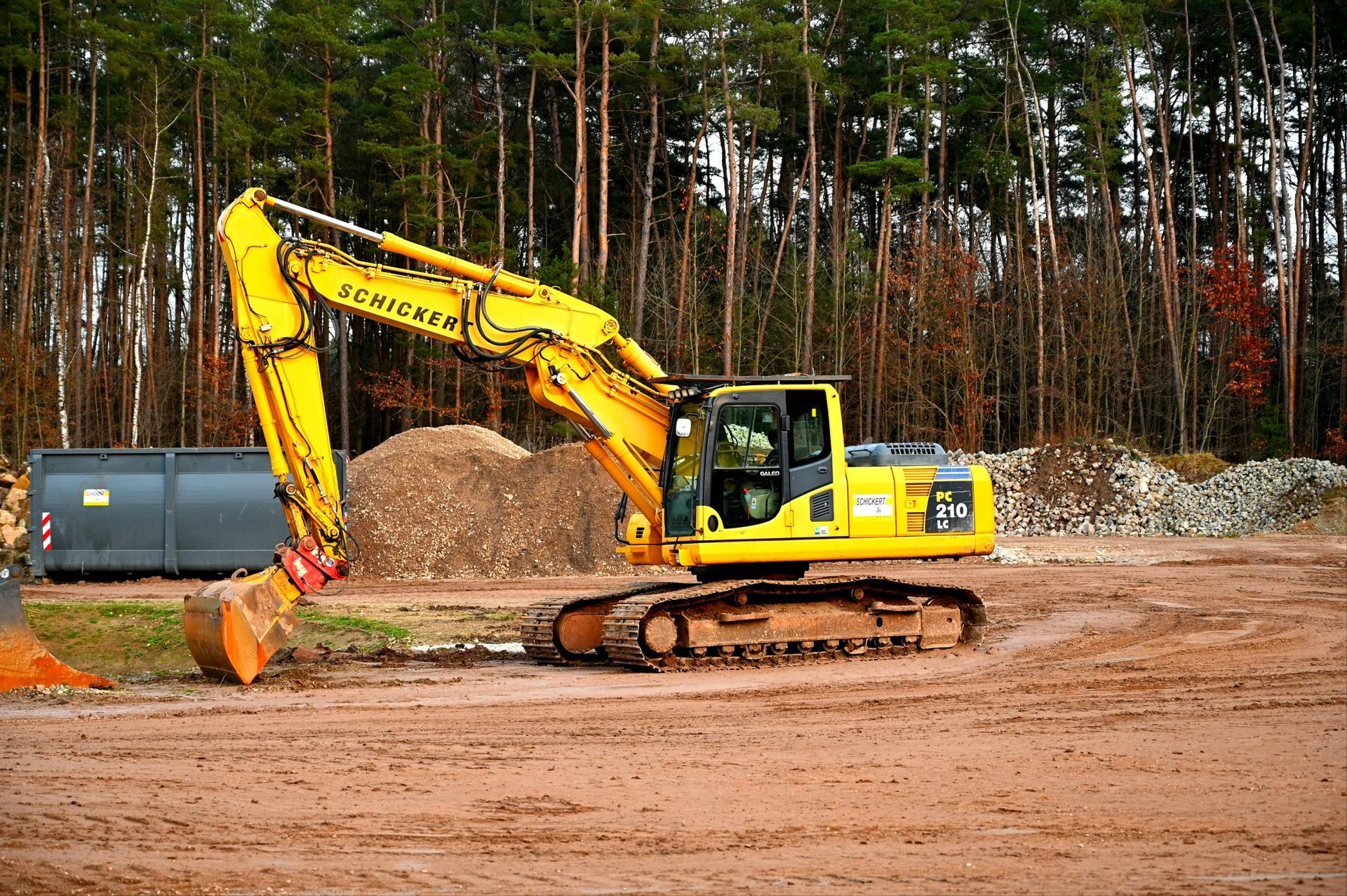 Yellow excavator digging dirt at a construction site in a wooded area