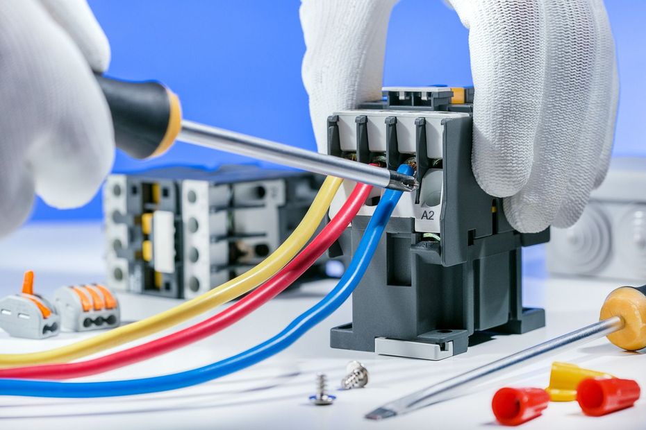 A person is working on an electrical device with a screwdriver.
