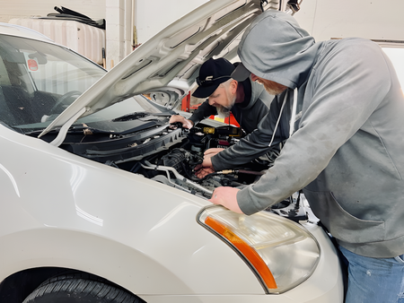 Mechanic working on a car engine with the hood open | Yunker Motorwerx