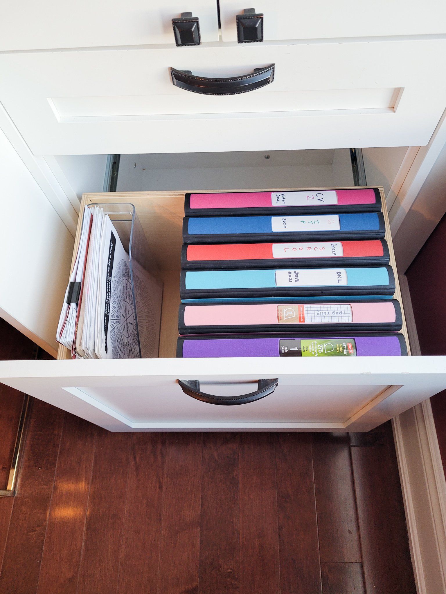 A drawer with a stack of binders in it
